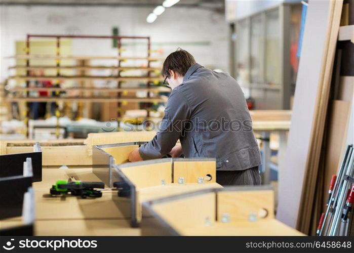 production, manufacture and industry concept - assembler working making furniture at factory workshop. assembler making furniture factory workshop