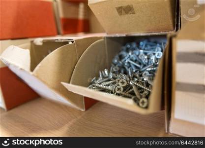 production, manufacture and industry concept - screws in cardboard boxes at workshop. screws in cardboard boxes at workshop