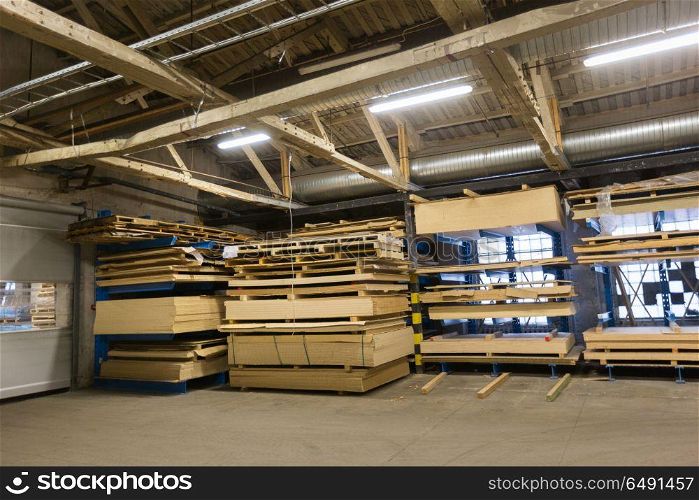production, manufacture and woodworking industry concept - boards storing at factory warehouse. boards storing at woodworking factory warehouse. boards storing at woodworking factory warehouse