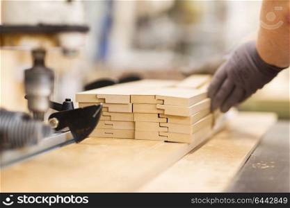 production, manufacture and woodworking industry concept - close up of worker or carpenter hand with boards at furniture factory workshop. close up of carpenter hand with boards at factory