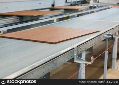production, manufacture and woodworking industry concept - wooden boards processing on conveyer at furniture factory workshop. wooden boards on conveyer at furniture factory