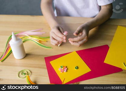 Production of compositions from long and narrow strips of paper twisted into spirals. With the hands of a child, make a card out of quilling, twist a strip of pink paper with an awl