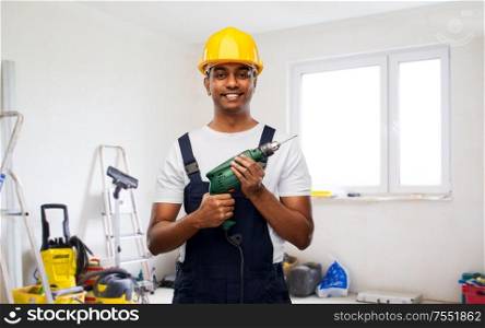 profession, building and repair concept - happy smiling indian repairman or builder in helmet with electric drill or perforator over empty room with construction equipment background. happy indian builder in helmet with electric drill