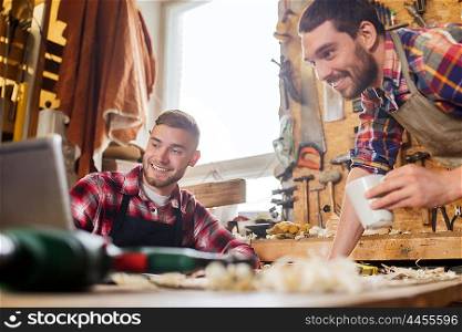 profession, carpentry, technology, woodwork and people concept - two carpenters with laptop computer at workshop