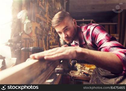 profession, carpentry, woodwork and people concept - carpenter testing wood plank evenness at workshop. carpenter working with wood plank at workshop. carpenter working with wood plank at workshop