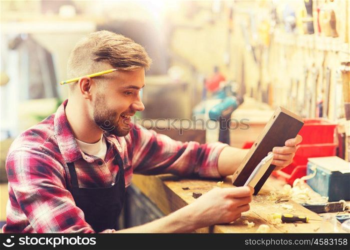 profession, carpentry, woodwork and people concept - carpenter with wood plank and notebook checking his notes at workshop. carpenter working with wood plank at workshop. carpenter working with wood plank at workshop