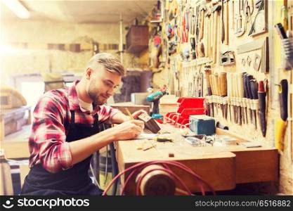 profession, carpentry, woodwork and people concept - carpenter with wood plank and notebook working at workshop. carpenter working with wood plank at workshop. carpenter working with wood plank at workshop