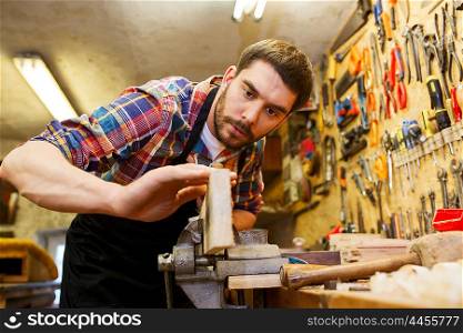 profession, carpentry, woodwork and people concept - carpenter working with plane and wood plank at workshop