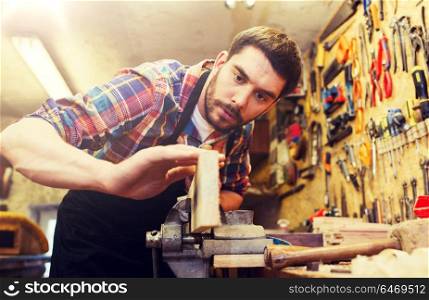 profession, carpentry, woodwork and people concept - carpenter working with plane and wood plank at workshop. carpenter working with plane and wood at workshop