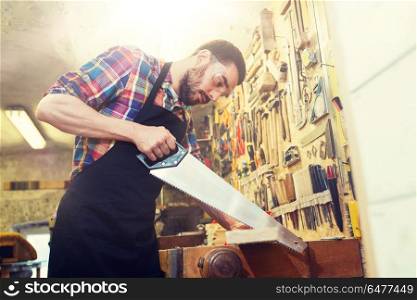 profession, carpentry, woodwork and people concept - carpenter working with saw and wood plank at workshop. carpenter working with saw and wood at workshop. carpenter working with saw and wood at workshop