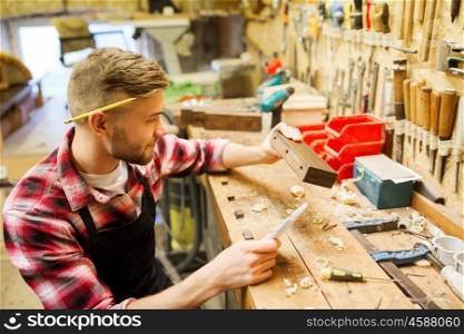 profession, carpentry, woodwork and people concept - carpenter working with wood plank at workshop