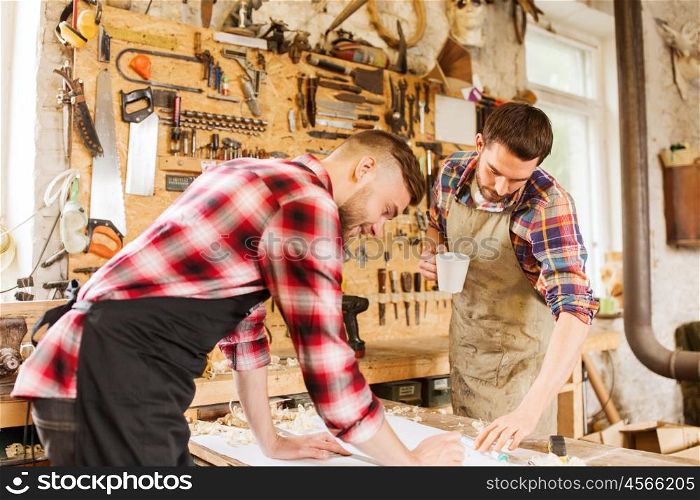 profession, carpentry, woodwork and people concept - two carpenters with ruler and blueprint at workshop