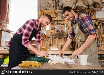 profession, carpentry, woodwork and people concept - two carpenters with ruler measuring blueprint at workshop. carpenters with ruler and blueprint at workshop