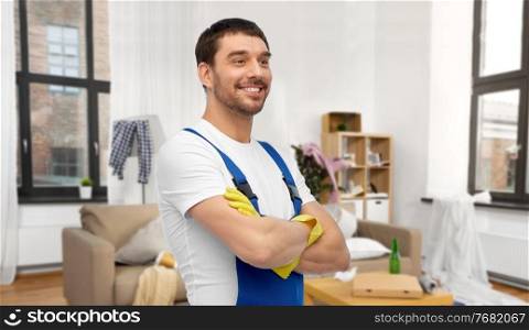 profession, cleaning service and building concept - happy smiling male worker or cleaner in overall and gloves over home room background. happy male worker or cleaner in gloves at home