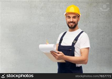 profession, construction and building concept - happy smiling male worker or builder in helmet with clipboard over grey concrete background. male worker or builder in helmet with clipboard