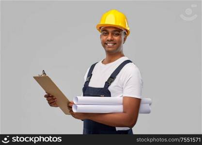 profession, construction and building - happy smiling indian builder in helmet with blueprint and clipboard over grey background. happy indian builder with blueprint and clipboard