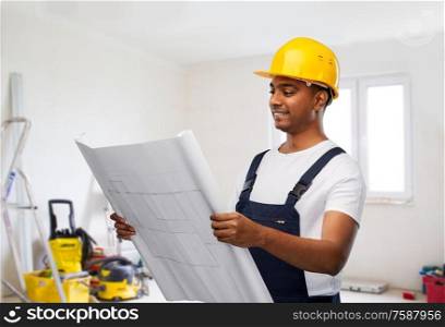 profession, construction and building - happy smiling indian builder in helmet with blueprint over room with working equipment at new home or apartment background. happy indian builder in helmet with blueprint