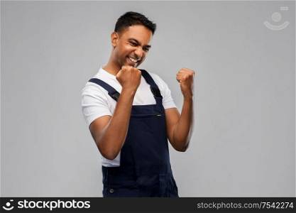 profession, construction and building - happy smiling indian worker or builder celebrating success over grey background. happy indian worker or builder celebrating success