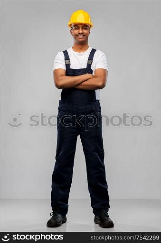 profession, construction and building - happy smiling indian worker or builder in helmet with crossed arms over grey background. happy indian worker or builder with crossed arms