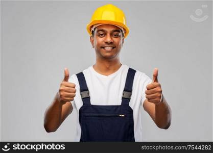 profession, construction and building - happy smiling indian worker or builder in helmet showing thumbs up over grey background. happy indian worker or builder showing thumbs up