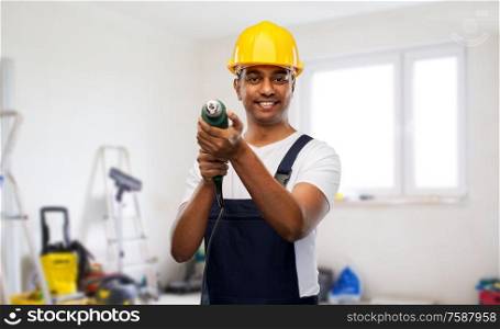 profession, construction and building - happy smiling indian worker or builder in helmet with electric drill or perforator over home or apartment room background. happy indian builder in helmet with electric drill
