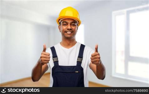 profession, construction and building - happy smiling indian worker or builder in helmet showing thumbs up over empty room at new home or apartment background. happy indian worker or builder showing thumbs up