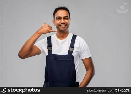 profession, construction and building - happy smiling indian worker or builder making phone call gesture over grey background. happy worker or builder making phone call gesture