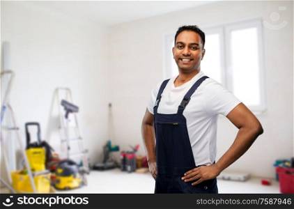 profession, construction and building - happy smiling indian worker or builder over room with working equipment at new home or apartment background. happy smiling indian worker or builder