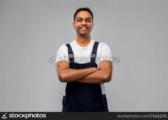 profession, construction and building - happy smiling indian worker or builder with crossed arms over grey background. happy indian worker or builder with crossed arms