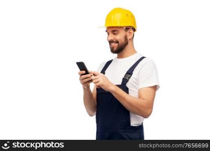 profession, construction and building - happy smiling male worker or builder in yellow helmet and overall with smartphone over white background. happy male worker or builder with smartphone