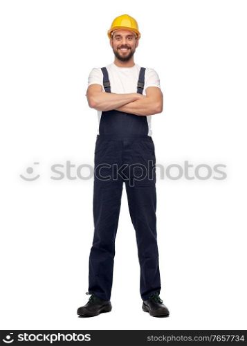 profession, construction and building - happy smiling male worker or builder in yellow helmet and overall with crossed arms over white background. male worker or builder with crossed arms