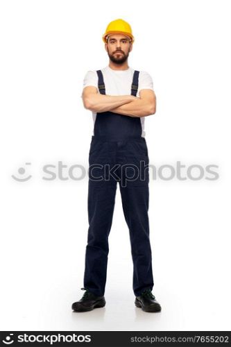 profession, construction and building - male worker or builder in yellow helmet and overall with crossed arms over white background. male worker or builder with crossed arms