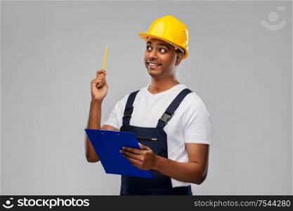 profession, construction and building - thinking indian worker or builder in helmet with clipboard and pencil having idea over grey background. builder with clipboard and pencil having idea