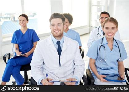 profession, medical education, health care, people and medicine concept - group of happy doctors on seminar in lecture hall at hospital