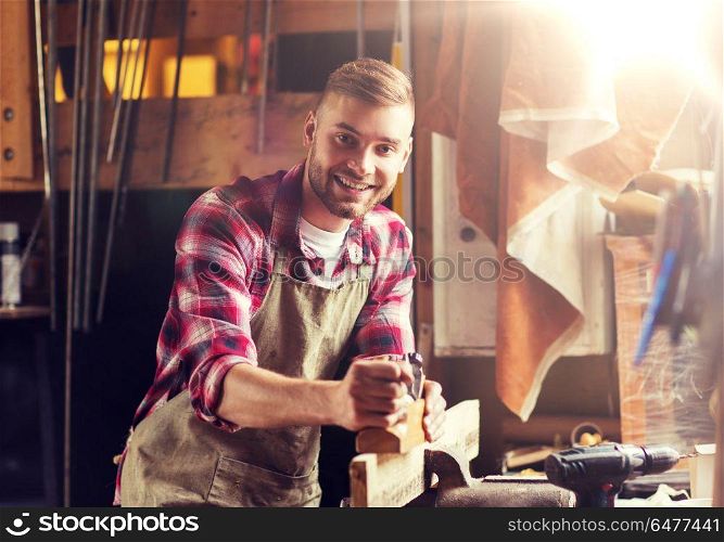 profession, people, carpentry, woodwork and people concept - happy carpenter with jointer planing wood plank at workshop. carpenter working with plane and wood at workshop. carpenter working with plane and wood at workshop
