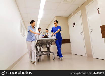 profession, people, health care, reanimation and medicine concept - group of medics or doctors carrying unconscious woman patient on hospital gurney to emergency