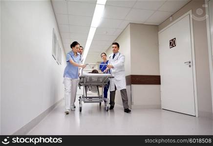 profession, people, health care, reanimation and medicine concept - group of medics or doctors carrying unconscious woman patient on hospital gurney to emergency