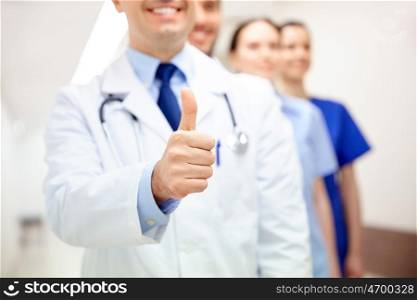 profession, people, healthcare, gesture and medicine concept - close up of happy medics or doctors at hospital corridor showing thumbs up