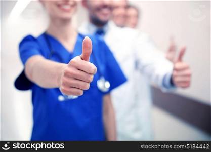 profession, people, healthcare, gesture and medicine concept - close up of happy medics or doctors at hospital corridor showing thumbs up. close up of doctors at hospital showing thumbs