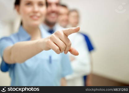 profession, people, healthcare, medicare and medicine concept - close up of happy medics or doctors pointing finger at hospital corridor