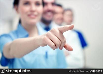profession, people, healthcare, medicare and medicine concept - close up of happy medics or doctors pointing finger at hospital corridor. close up of doctor pointing finger at hospital