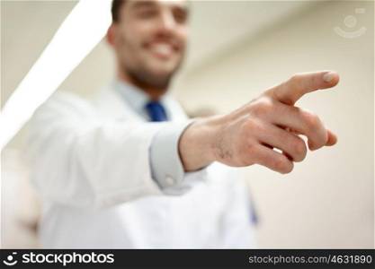 profession, people, medicare, healthcare and medicine concept - close up of happy medic or doctor pointing finger at hospital corridor