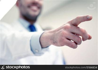 profession, people, medicare, healthcare and medicine concept - close up of happy medic or doctor pointing finger at hospital corridor. close up of doctor pointing finger at hospital