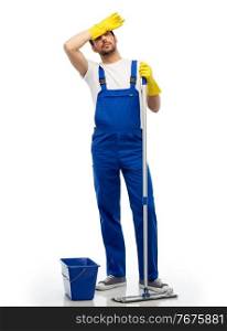 profession, service and people - tired male worker or cleaner in overal and gloves cleaning floor with mop and bucket over white background. tired cleaner cleaning floor with mop and bucket