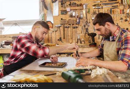 profession, technology and people concept - two workmen with tablet pc computer, dividers or compass and blueprint at workshop