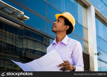 Professional architect in helmet looking away outside modern building.