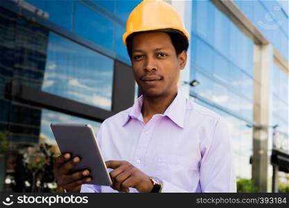 Professional architect in helmet with digital tablet outdoors.