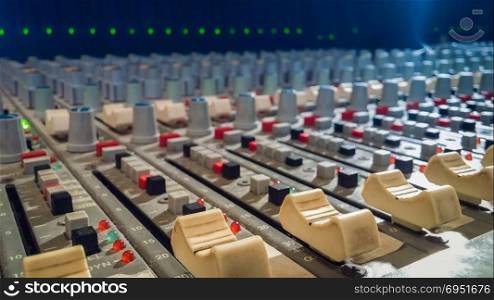 Professional audio mixing console with faders in recording studio.