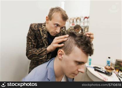 Professional barber examining male customer&rsquo;s in shop