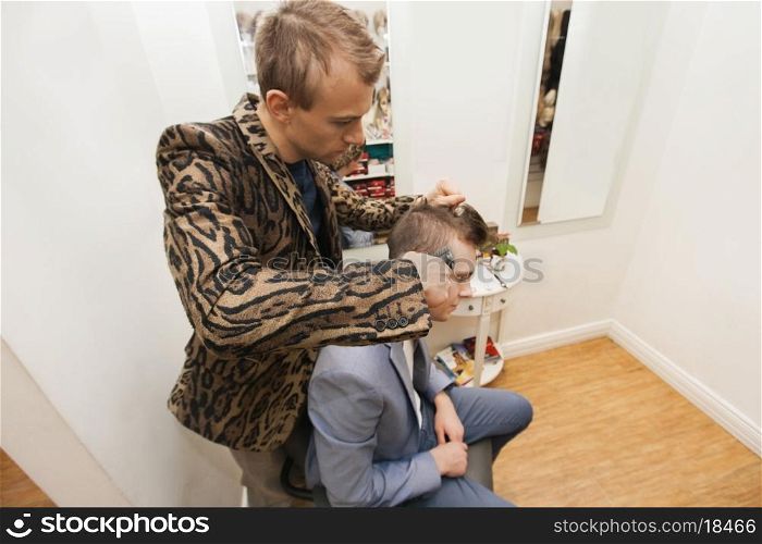 Professional barber shaving male customer's hair in shop
